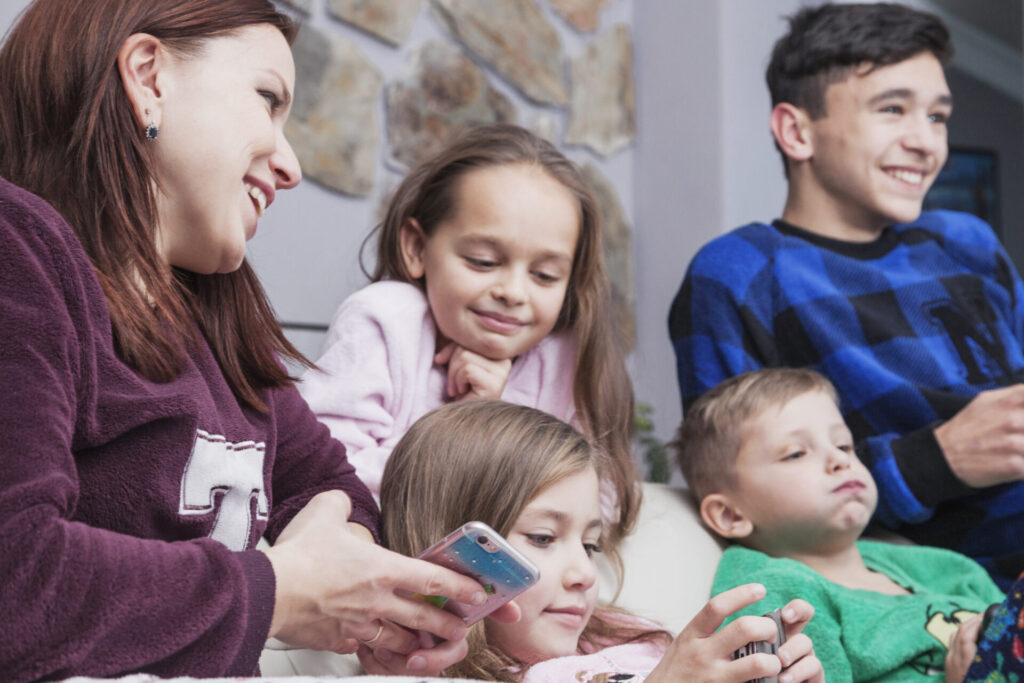 A family is gathered on a couch, all looking at their mobile phones.
