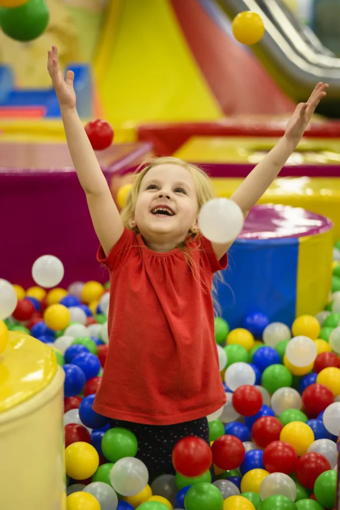 Kids and adults jumping at an indoor trampoline park with foam pits and basketball hoops.