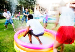 Parent cleaning a bounce house with soap and water outdoors
