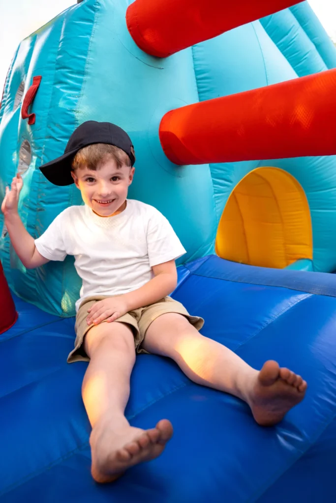 Children bouncing on a colorful inflatable bouncy castle set up outdoors for a party